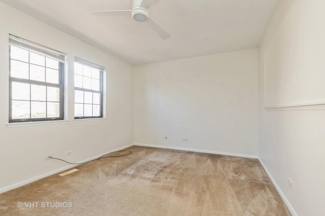 carpeted spare room featuring visible vents, ceiling fan, and baseboards