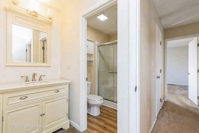 bathroom featuring a stall shower, baseboards, vanity, and toilet