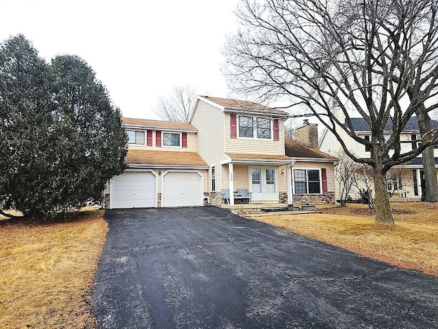 view of front of house with a chimney, an attached garage, stone siding, driveway, and a front lawn