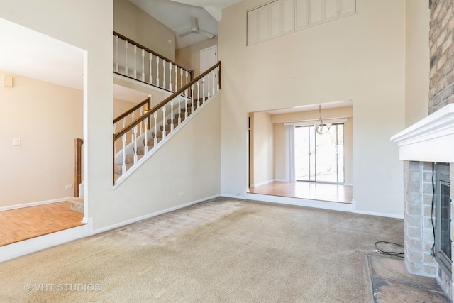 unfurnished living room featuring a fireplace, stairway, a high ceiling, carpet flooring, and baseboards