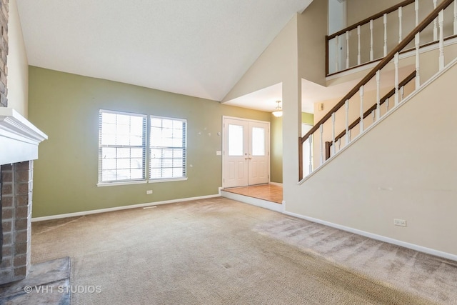 unfurnished living room featuring high vaulted ceiling, a fireplace, baseboards, stairs, and carpet