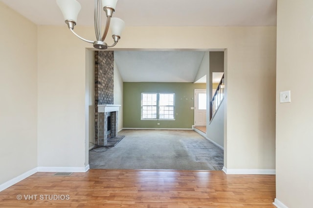 unfurnished living room with wood finished floors, a fireplace, baseboards, and stairs