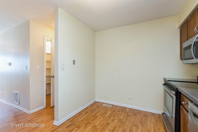 kitchen featuring stainless steel appliances, visible vents, light wood-style floors, and baseboards