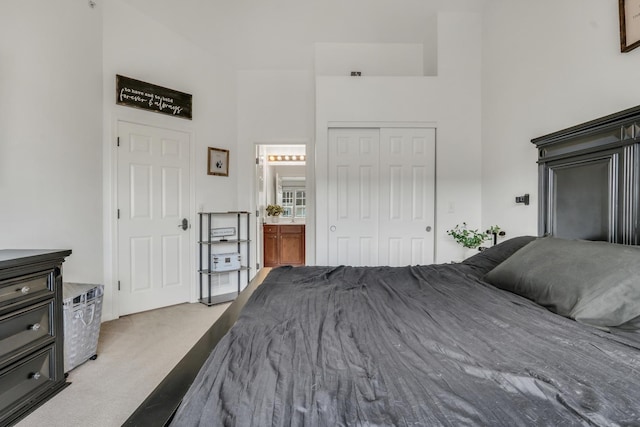 bedroom with a towering ceiling, connected bathroom, a closet, and carpet flooring