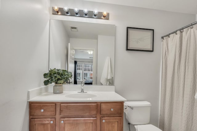 full bathroom with toilet, vanity, visible vents, and connected bathroom