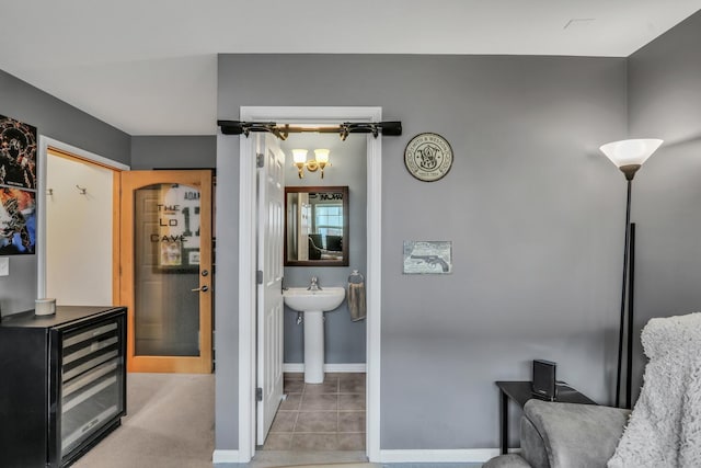 interior space with wine cooler, a sink, and baseboards