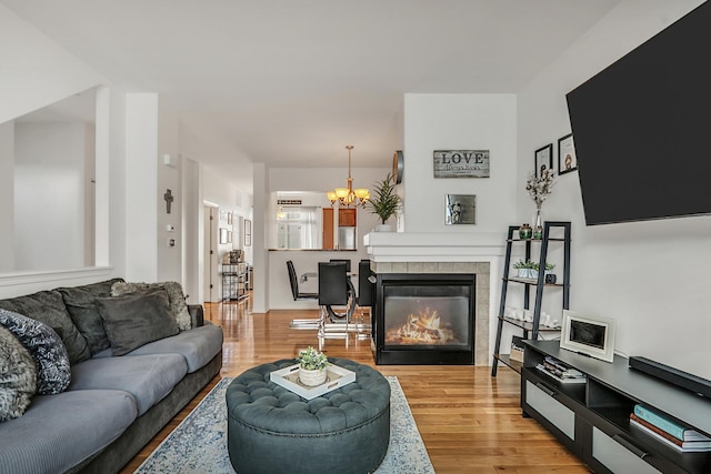 living area featuring light wood-style floors, a notable chandelier, and a fireplace