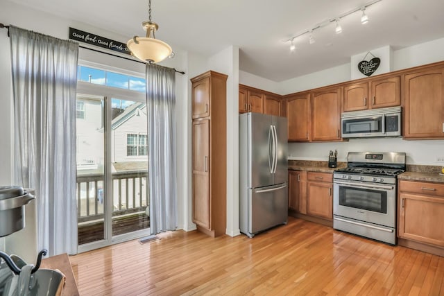 kitchen featuring brown cabinets, light wood finished floors, dark countertops, visible vents, and appliances with stainless steel finishes