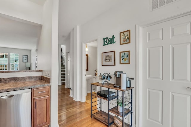 interior space with baseboards, visible vents, dishwasher, stairs, and light wood-style floors