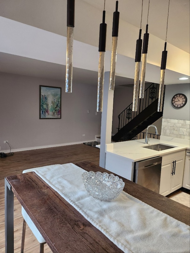 interior space with tasteful backsplash, stainless steel dishwasher, light wood-style floors, a sink, and baseboards