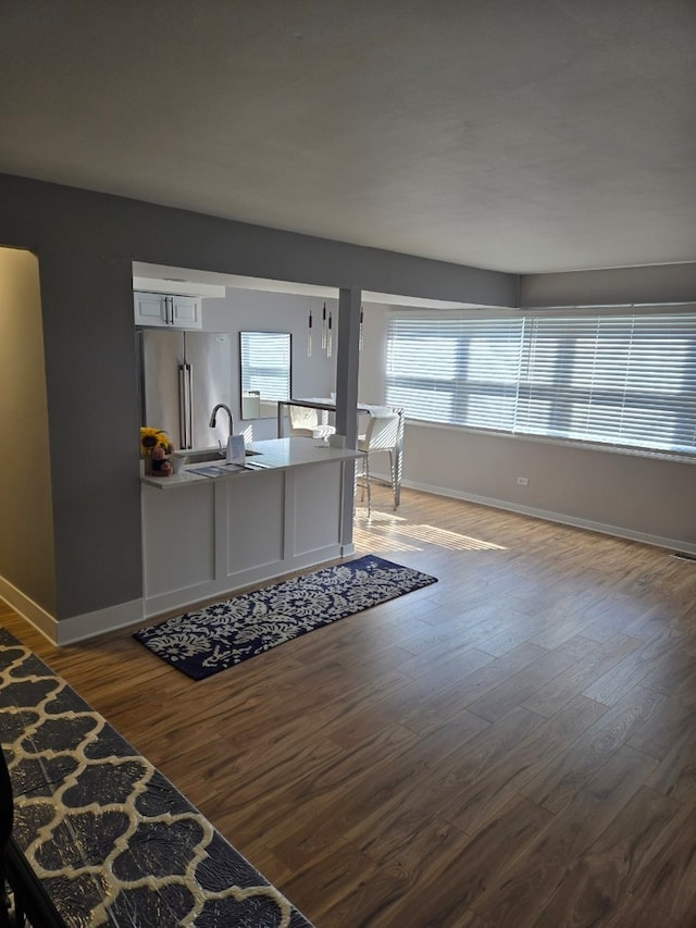 interior space with freestanding refrigerator, white cabinets, baseboards, and wood finished floors