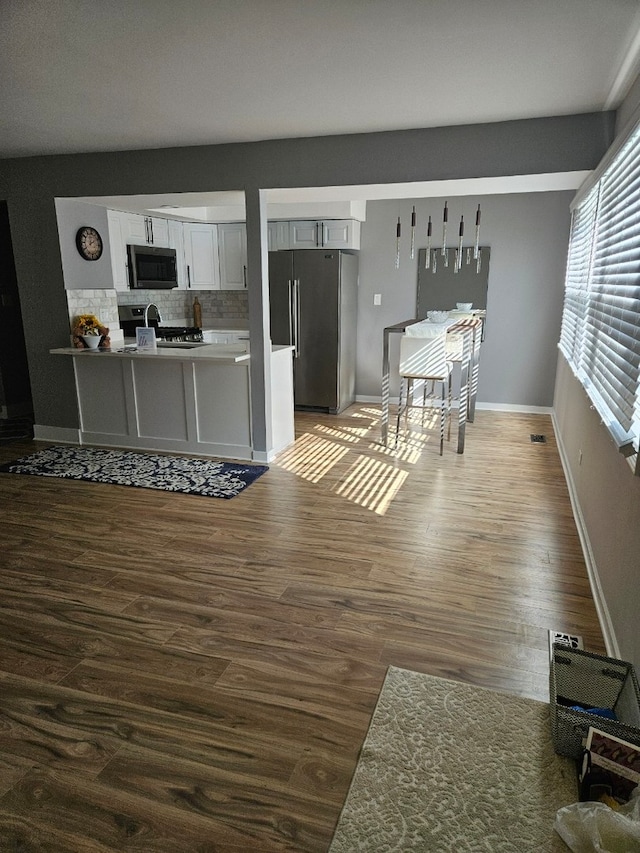 kitchen with baseboards, decorative backsplash, appliances with stainless steel finishes, dark wood-type flooring, and white cabinetry