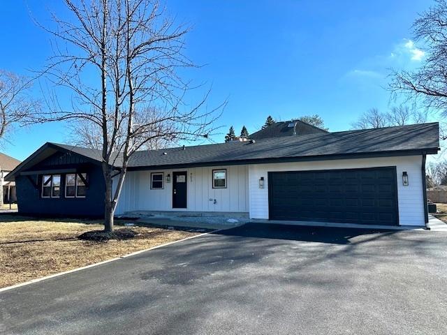 ranch-style home with a garage, board and batten siding, and aphalt driveway