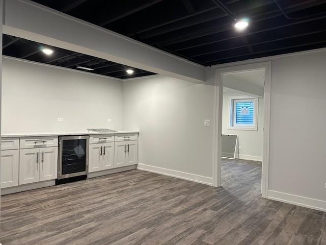 bar with wine cooler, dark wood-type flooring, a dry bar, and baseboards