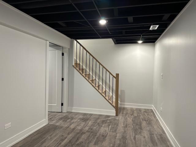 finished basement with stairs, wood finished floors, and baseboards