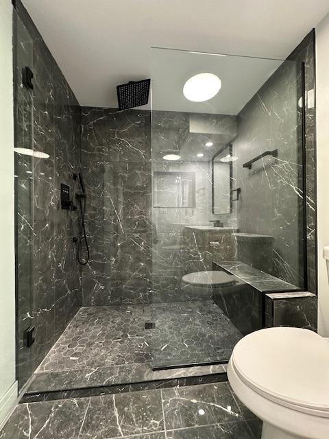 full bathroom with marble finish floor, a marble finish shower, and toilet