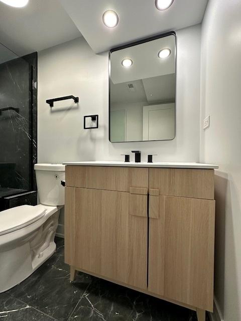 full bath featuring toilet, recessed lighting, vanity, marble finish floor, and a shower