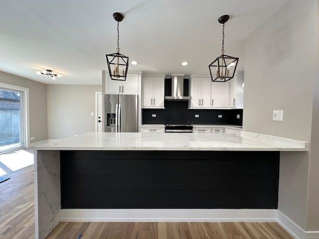 kitchen featuring light wood-style flooring, a peninsula, white cabinets, stainless steel fridge with ice dispenser, and wall chimney exhaust hood