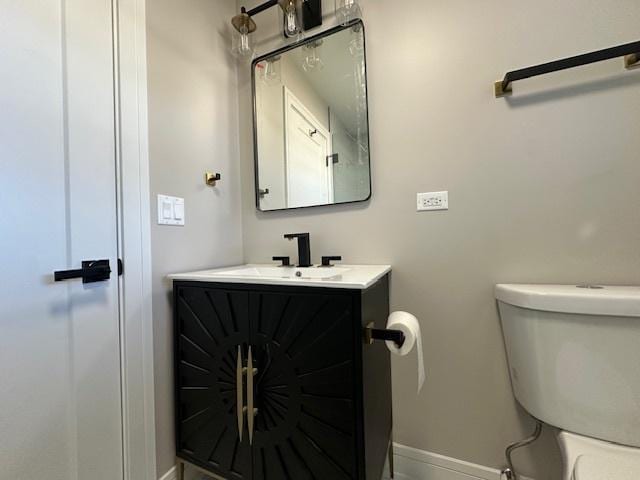 half bathroom with toilet, baseboards, and vanity