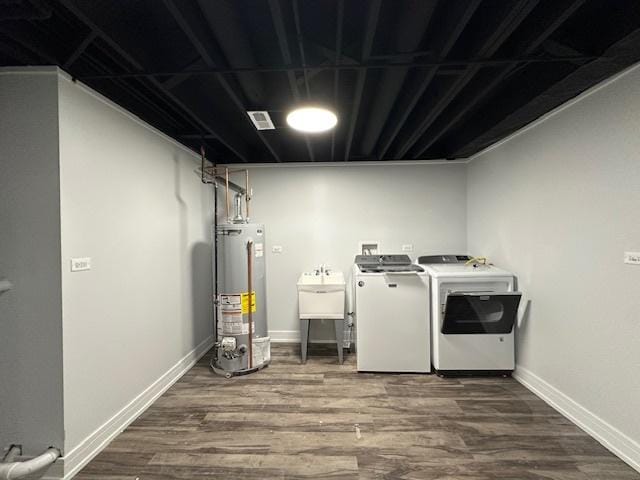 washroom with baseboards, gas water heater, dark wood-style floors, independent washer and dryer, and a sink