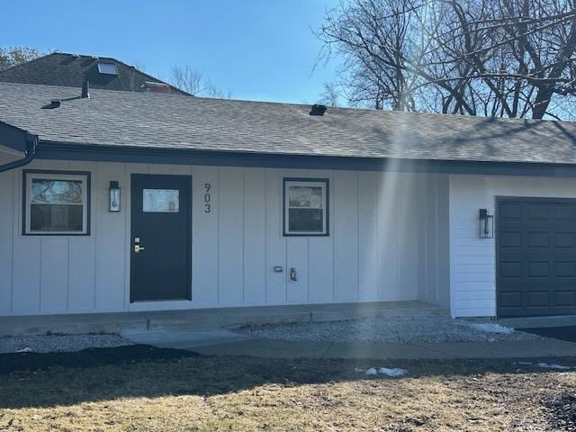 property entrance featuring roof with shingles and an attached garage