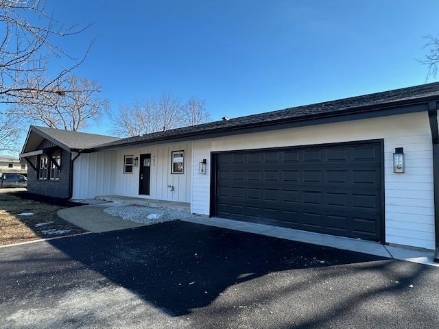 ranch-style house with aphalt driveway, a garage, and board and batten siding