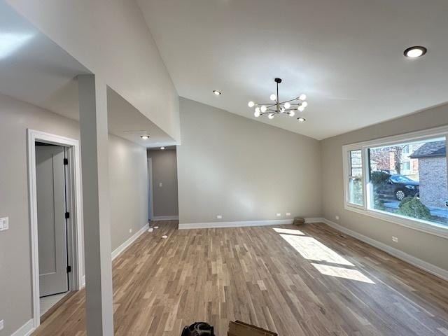 empty room featuring light wood-type flooring, an inviting chandelier, baseboards, and vaulted ceiling