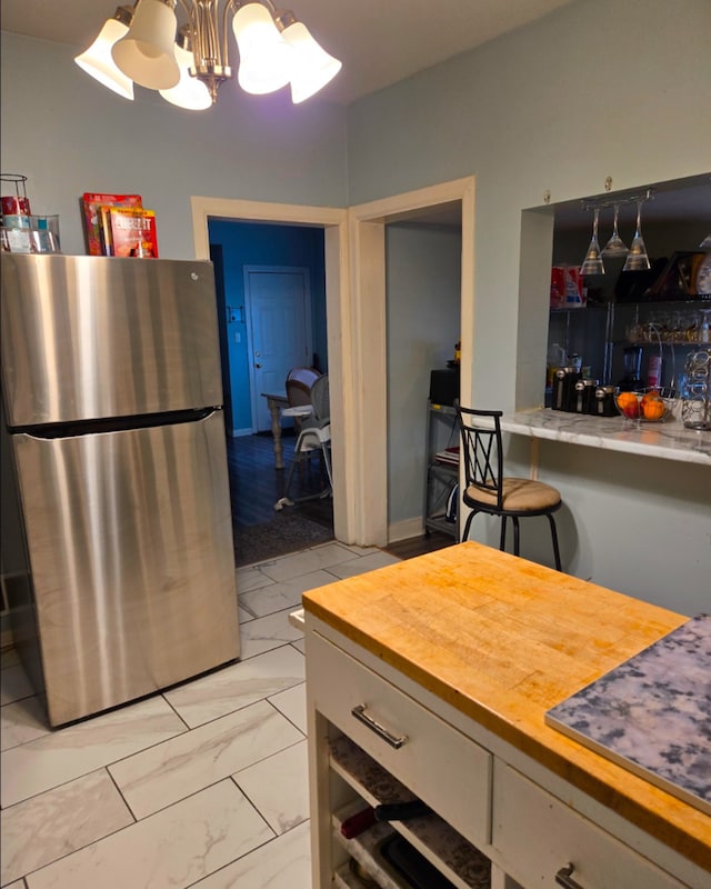 kitchen with marble finish floor, wood counters, freestanding refrigerator, and an inviting chandelier