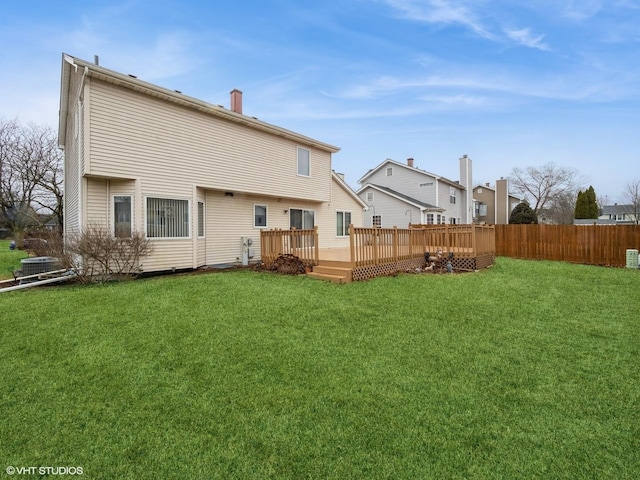 back of property featuring a deck, a lawn, and fence