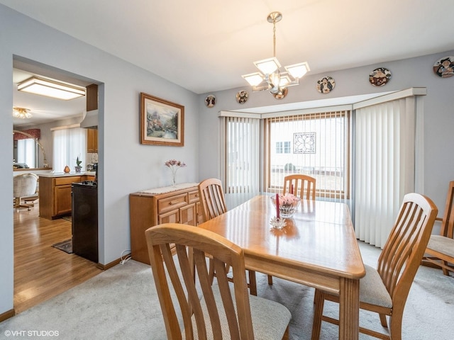 dining area with light colored carpet and an inviting chandelier