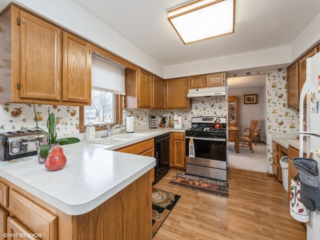 kitchen featuring light countertops, stainless steel gas stove, a sink, dishwasher, and under cabinet range hood