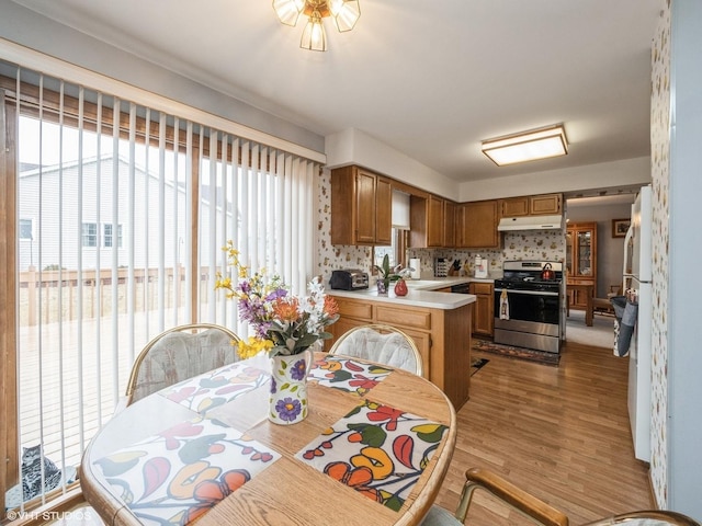 kitchen featuring light countertops, plenty of natural light, under cabinet range hood, and gas range