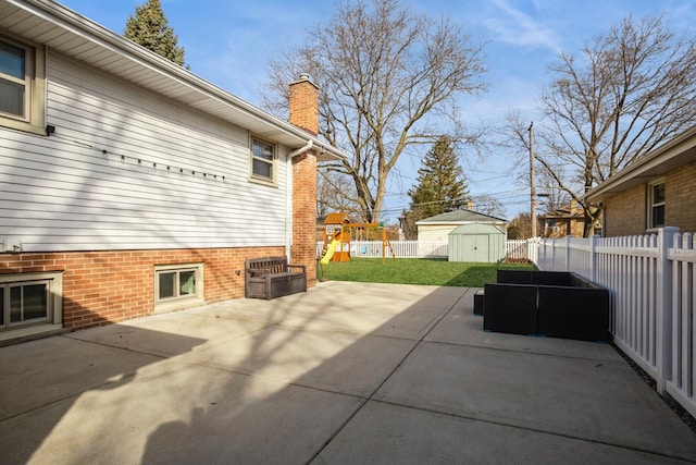 view of patio featuring a playground, an outdoor structure, a fenced backyard, and a storage shed