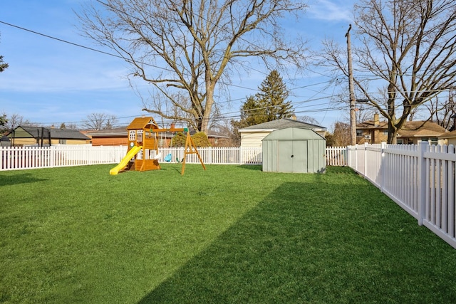 view of yard with a playground, an outdoor structure, a fenced backyard, and a storage unit