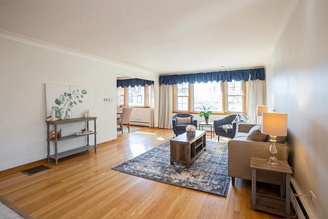 living area with a baseboard heating unit, a healthy amount of sunlight, visible vents, and wood finished floors