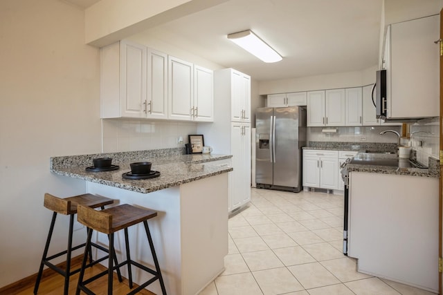 kitchen featuring a peninsula, white cabinetry, stainless steel appliances, and a kitchen breakfast bar