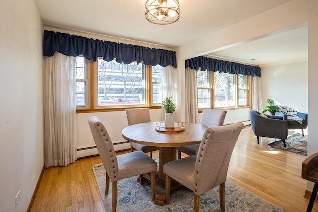 dining area featuring light wood-type flooring, an inviting chandelier, and a baseboard radiator