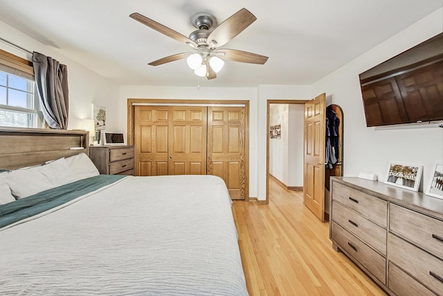 bedroom featuring light wood-type flooring, ceiling fan, baseboards, and a closet