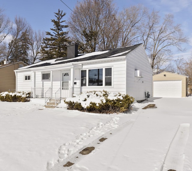 view of front of house featuring a detached garage, a chimney, and an outdoor structure