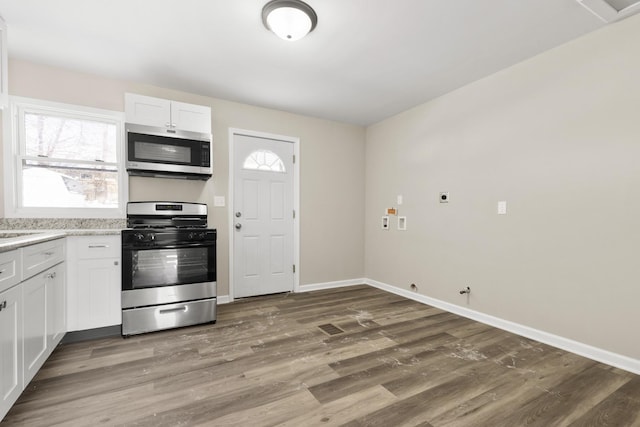 kitchen with baseboards, stainless steel appliances, wood finished floors, and white cabinets