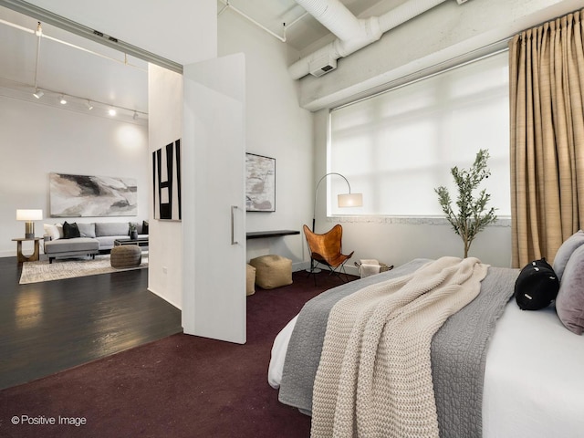 bedroom featuring rail lighting and wood finished floors