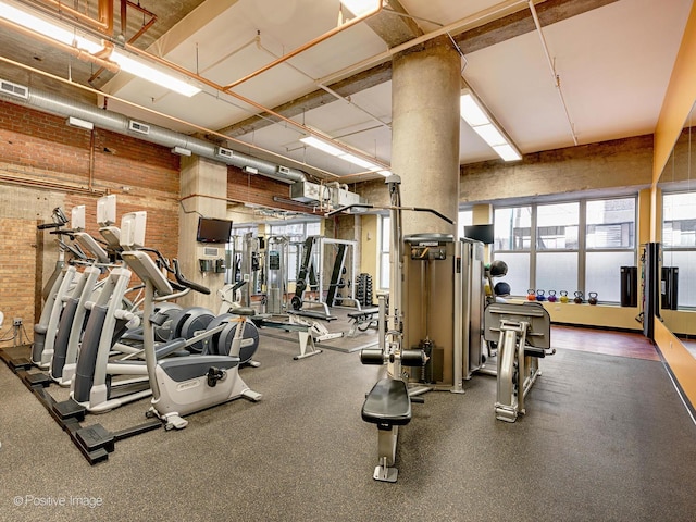 workout area with visible vents, brick wall, plenty of natural light, and a towering ceiling