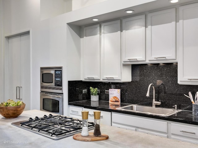 kitchen featuring appliances with stainless steel finishes, white cabinets, a sink, and backsplash