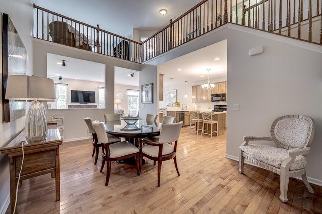 dining room with a towering ceiling, light wood-style floors, baseboards, and an inviting chandelier