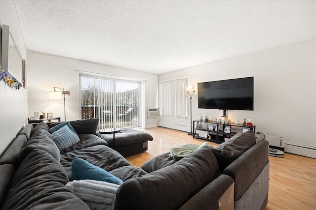 living area featuring light wood-style flooring, baseboard heating, and a textured ceiling