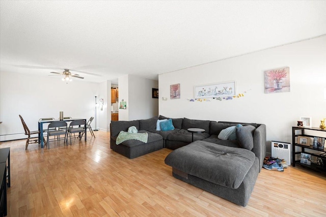 living area with a textured ceiling, light wood-style floors, and a ceiling fan