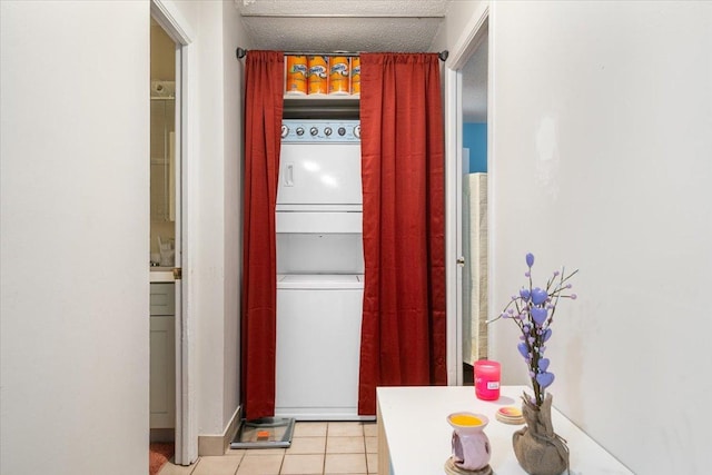 corridor with stacked washer and dryer, light tile patterned flooring, and a textured ceiling