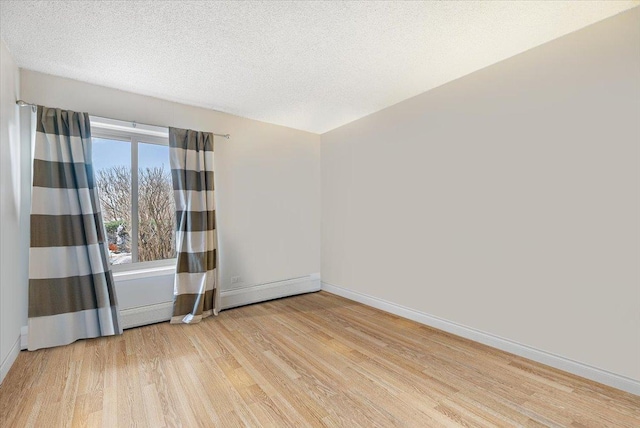 empty room featuring wood finished floors, baseboards, and a textured ceiling