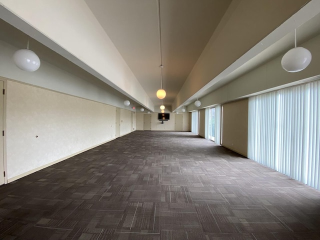 unfurnished room with dark carpet and high vaulted ceiling