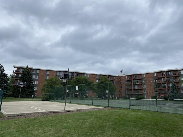 view of tennis court featuring community basketball court, a yard, and fence